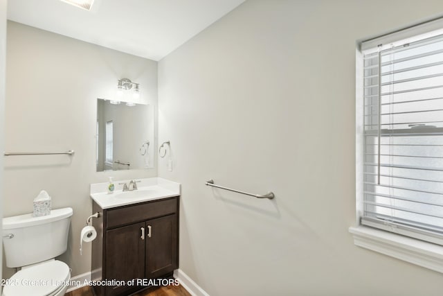 bathroom featuring toilet, vanity, baseboards, and wood finished floors