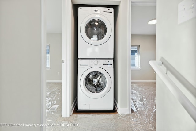 laundry area featuring laundry area, stacked washer and dryer, and baseboards