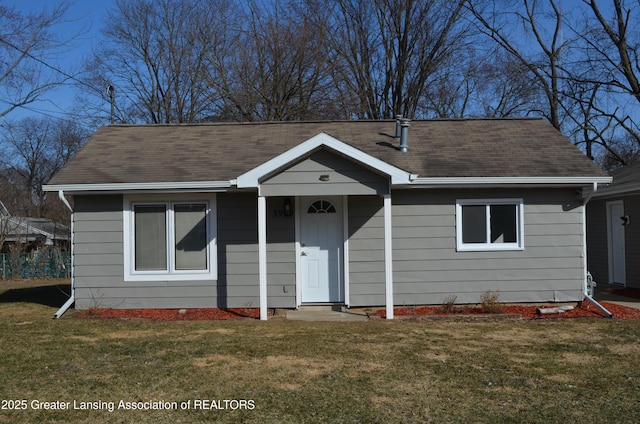 view of front facade with a front lawn and a shingled roof