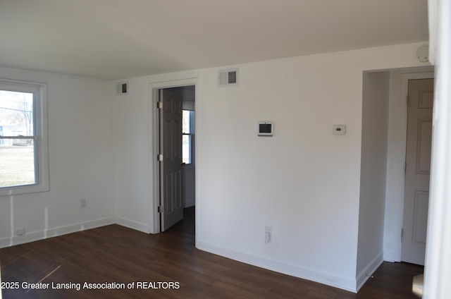 spare room with visible vents, baseboards, and dark wood-type flooring