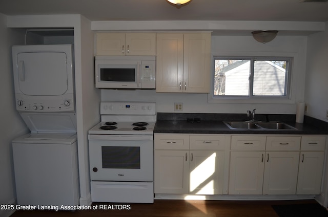 kitchen featuring white appliances, a sink, white cabinets, stacked washer and clothes dryer, and dark countertops