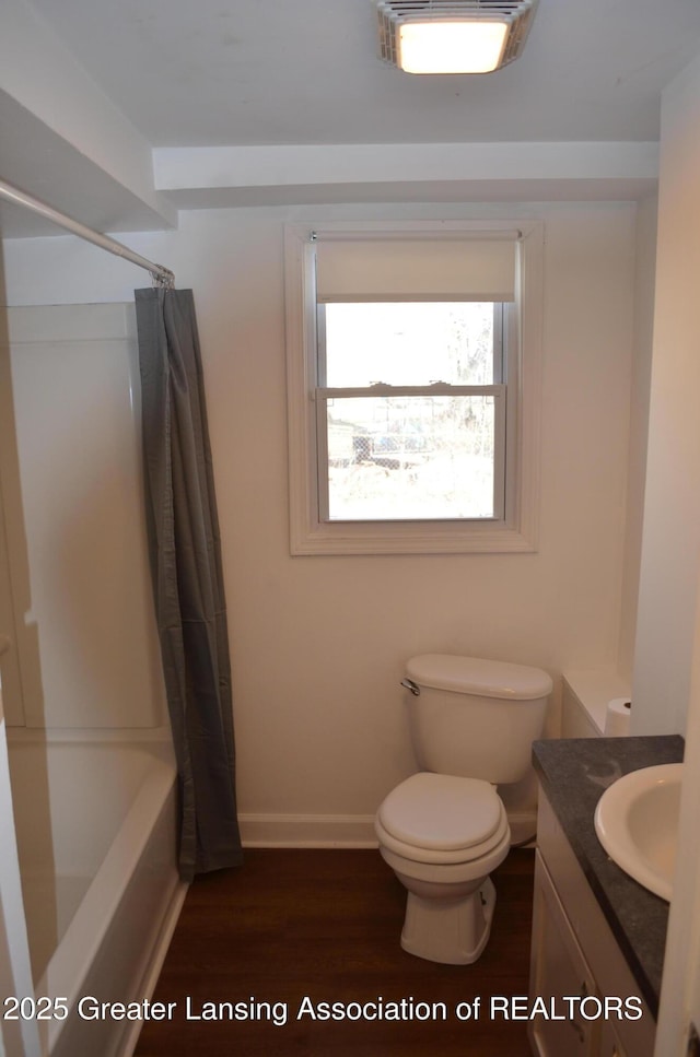 bathroom featuring toilet, shower / bath combo, wood finished floors, baseboards, and vanity