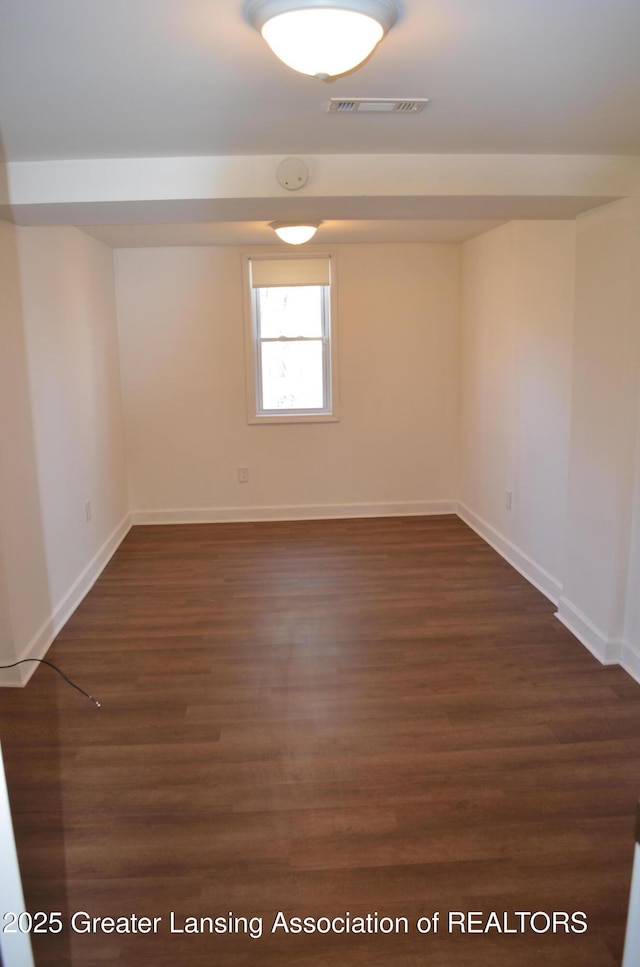 unfurnished room featuring visible vents, baseboards, and dark wood finished floors