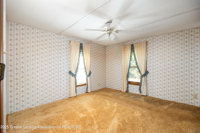 carpeted empty room featuring ceiling fan and wallpapered walls