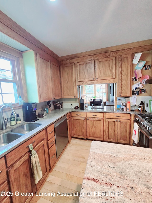 kitchen with dishwashing machine, light countertops, light wood-style floors, and a sink