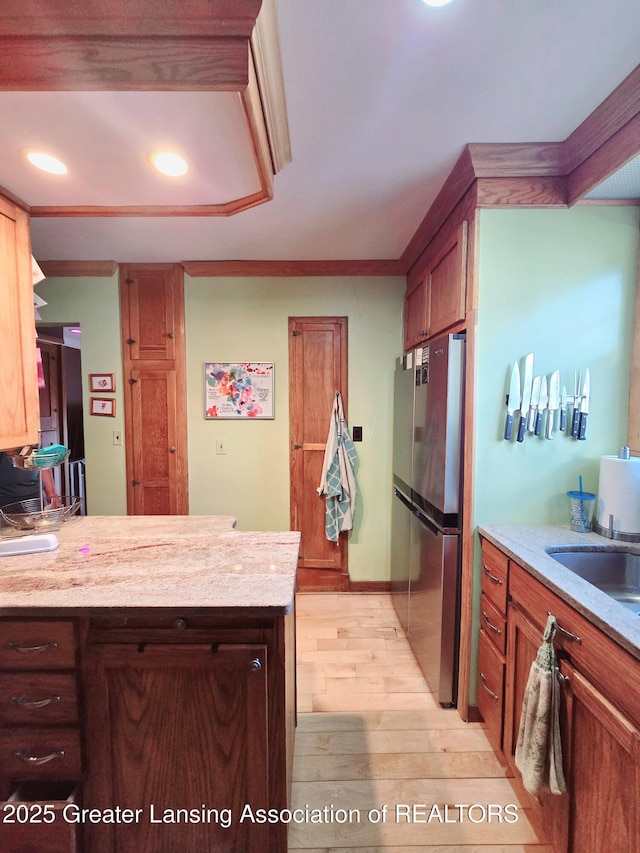 kitchen with a peninsula, light wood-style floors, freestanding refrigerator, and a sink