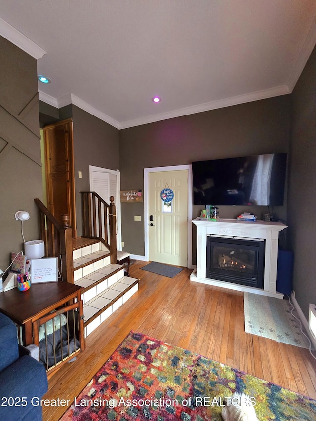 living room featuring hardwood / wood-style flooring, stairway, and crown molding