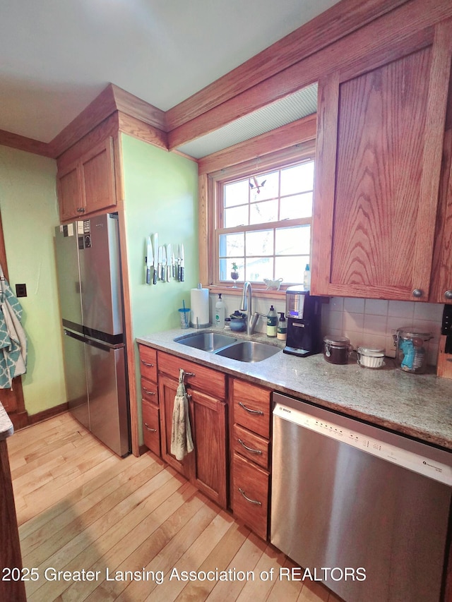 kitchen featuring light wood finished floors, appliances with stainless steel finishes, light countertops, and a sink