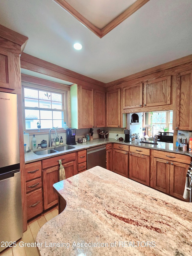 kitchen with brown cabinets, light tile patterned floors, stainless steel appliances, and a sink