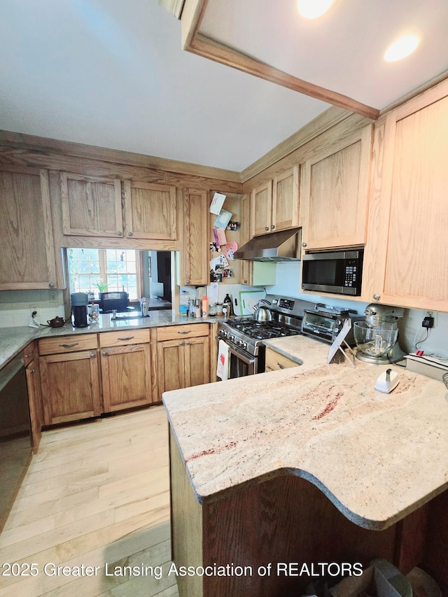 kitchen featuring light wood finished floors, under cabinet range hood, a toaster, a peninsula, and stainless steel appliances