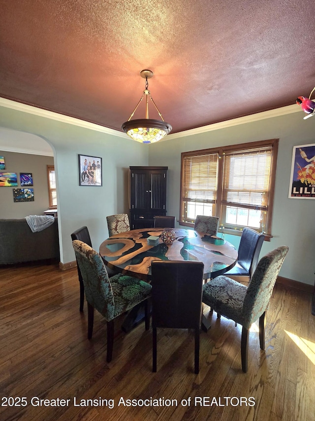 dining space featuring a textured ceiling, wood finished floors, arched walkways, and ornamental molding