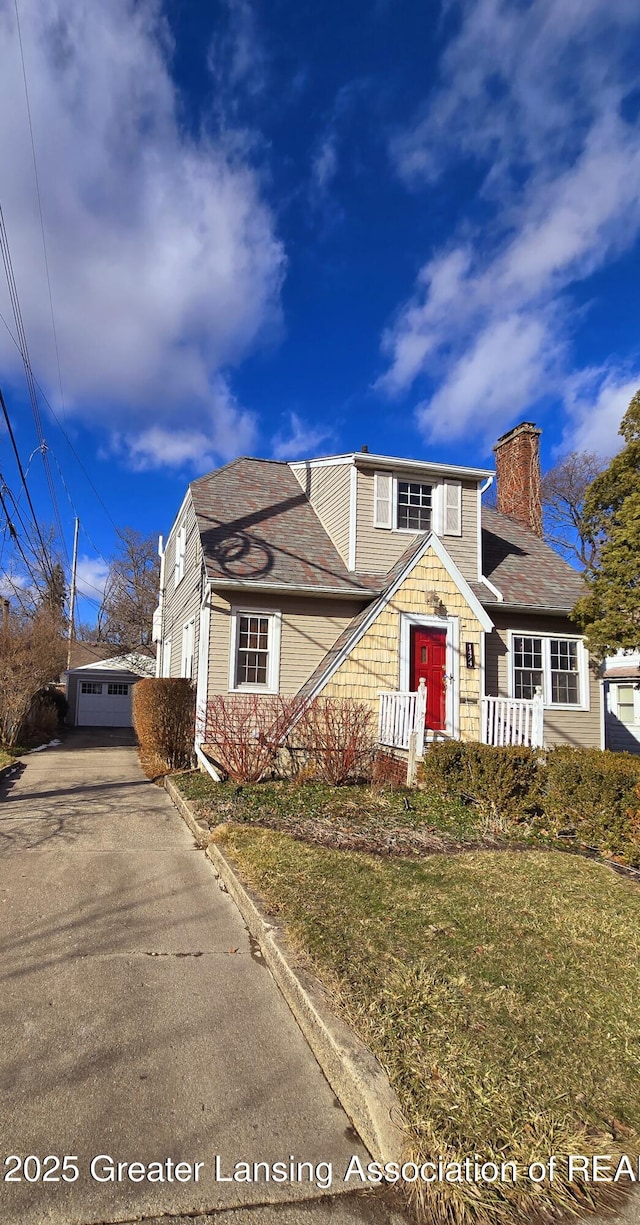 traditional-style home with a front lawn, a chimney, and an outdoor structure