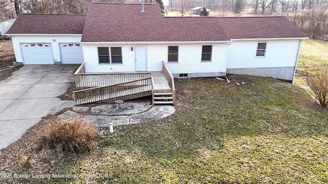 back of house with an attached garage, a shingled roof, driveway, and a yard