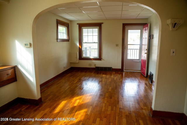 entrance foyer featuring a drop ceiling, arched walkways, visible vents, and wood finished floors