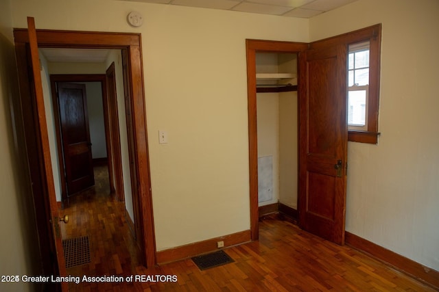 unfurnished bedroom with a closet, visible vents, baseboards, and wood finished floors