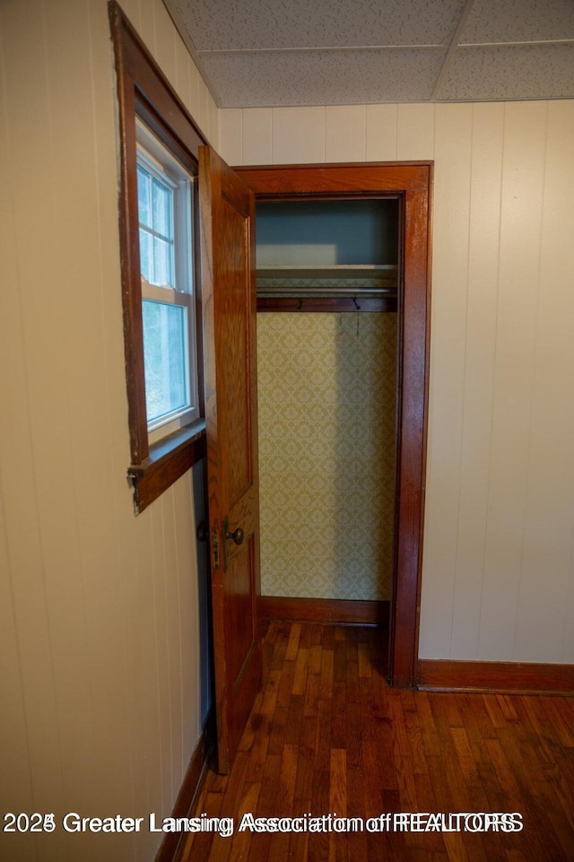 corridor featuring baseboards and dark wood-style floors