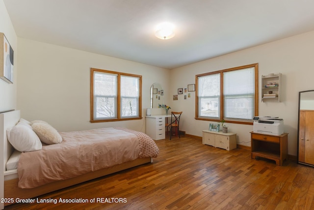 bedroom with baseboards, multiple windows, and hardwood / wood-style flooring