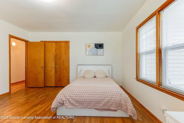 bedroom featuring light wood-type flooring, a closet, and baseboards