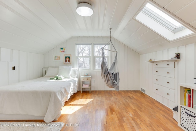 bedroom with light wood finished floors, visible vents, and lofted ceiling with skylight