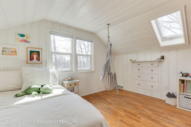 bedroom with vaulted ceiling with skylight and light wood finished floors