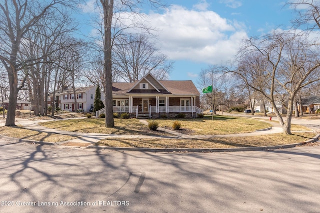 view of front of house featuring roof with shingles, a porch, and a front lawn