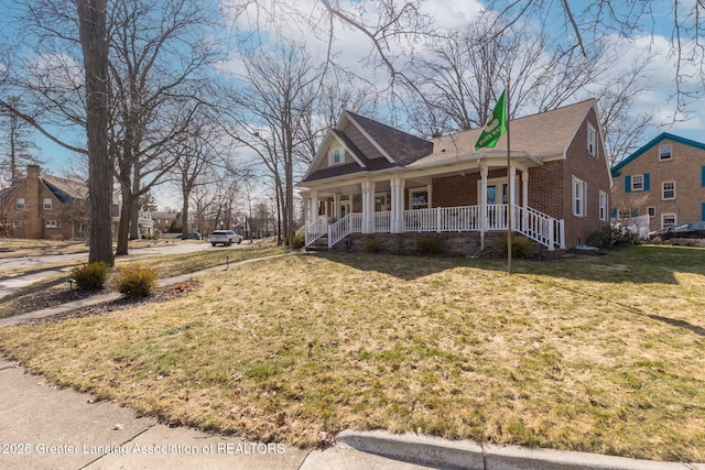 view of front of house featuring a porch, brick siding, and a front lawn