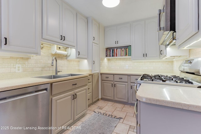 kitchen with backsplash, light countertops, stainless steel appliances, white cabinetry, and a sink