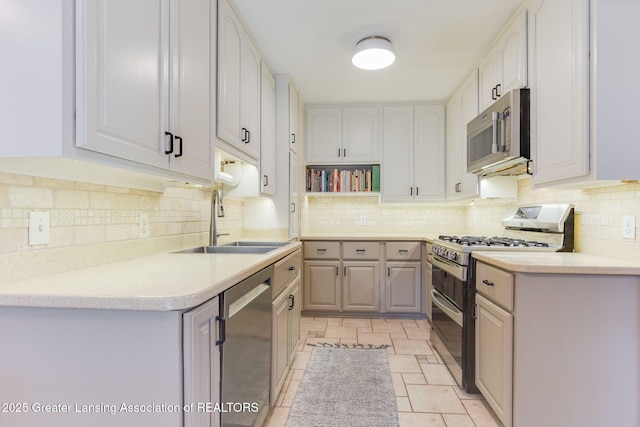 kitchen featuring tasteful backsplash, stainless steel appliances, light countertops, and a sink