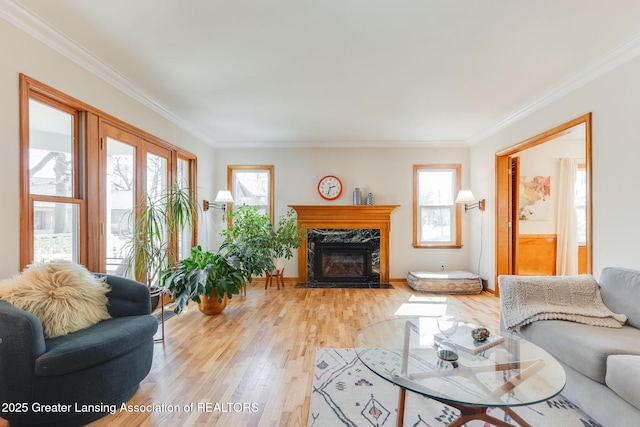 living area with light wood-type flooring, a high end fireplace, and crown molding