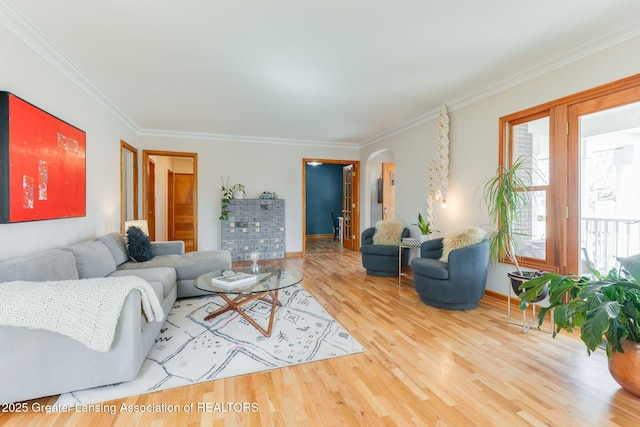 living room with wood finished floors, arched walkways, and ornamental molding