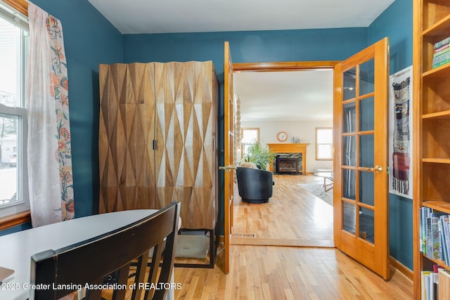 interior space featuring a fireplace, wood finished floors, visible vents, and french doors