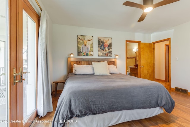 bedroom featuring ceiling fan, visible vents, multiple windows, and wood finished floors