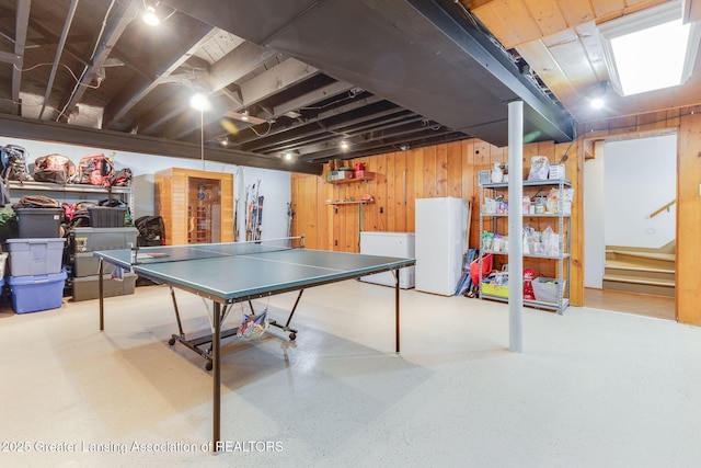 recreation room featuring wooden walls and speckled floor