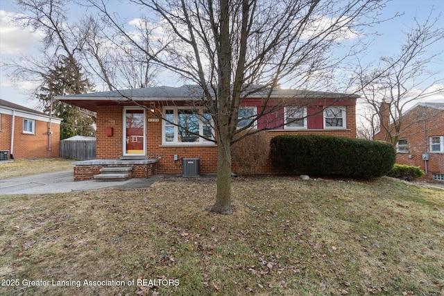 view of front of property featuring brick siding, central AC unit, and a front lawn