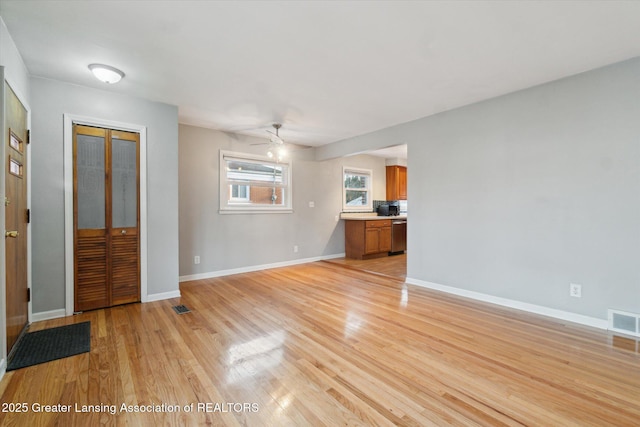 unfurnished living room with light wood-type flooring, visible vents, baseboards, and ceiling fan