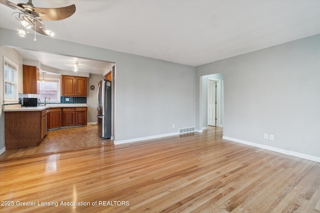 unfurnished living room featuring light wood finished floors, visible vents, ceiling fan, and baseboards