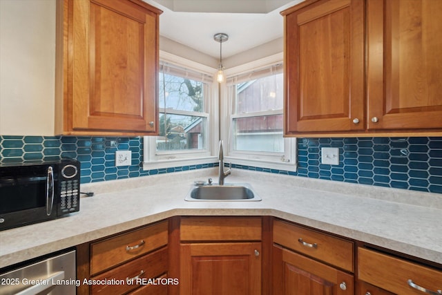 kitchen featuring decorative backsplash, light countertops, black microwave, and a sink