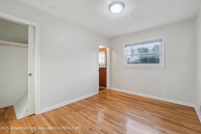 unfurnished bedroom with a closet, baseboards, light wood-style floors, and a textured ceiling