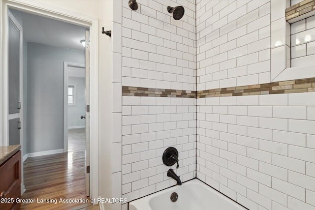 full bath with baseboards, shower / tub combination, wood finished floors, and vanity