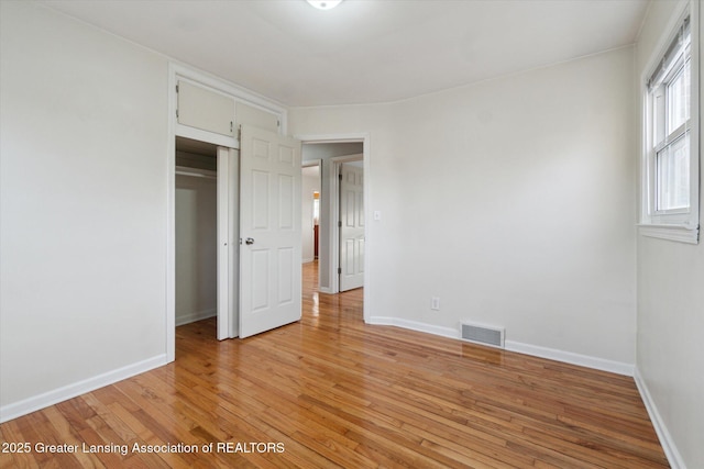 unfurnished bedroom with light wood-type flooring, baseboards, a closet, and visible vents