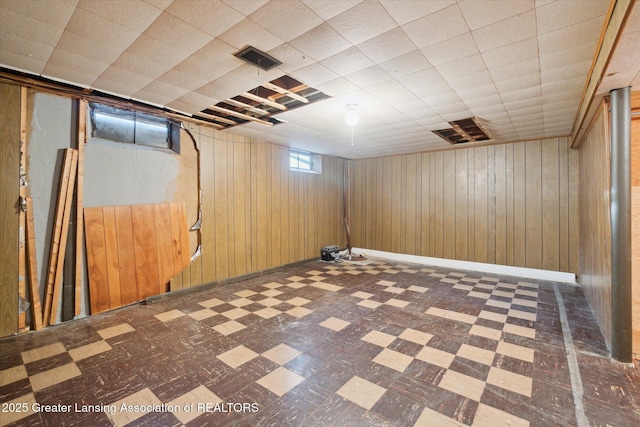 basement with tile patterned floors, baseboards, and wooden walls