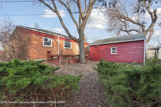 back of house with brick siding and an outbuilding