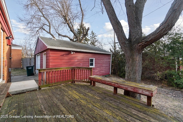 wooden terrace featuring an outbuilding and fence