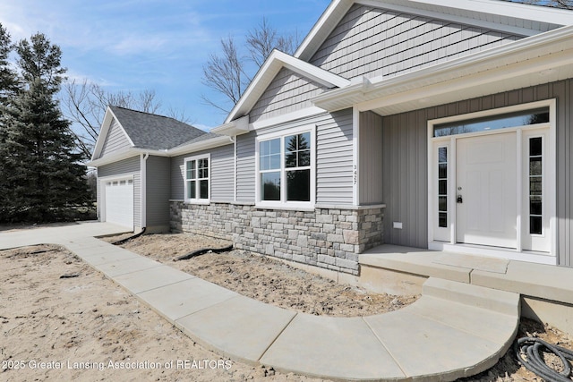 doorway to property featuring concrete driveway, a garage, and stone siding