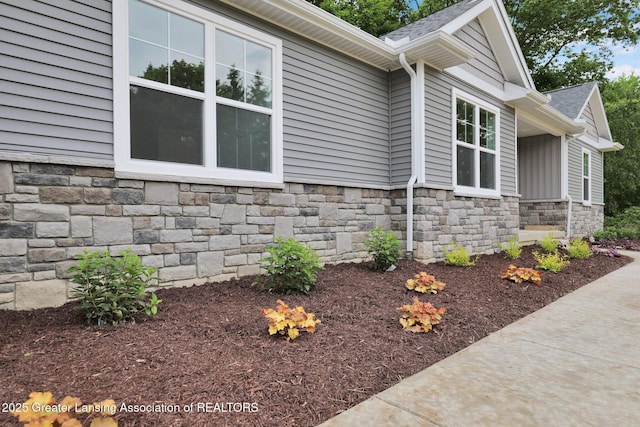3427 W Broadmoor Dr, Lansing, MI 48906 - view of property exterior featuring stone siding and roof with shingles
