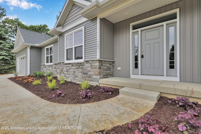 3427 W Broadmoor Dr, Lansing, MI 48906 - property entrance with stone siding, a garage, board and batten siding, and a porch