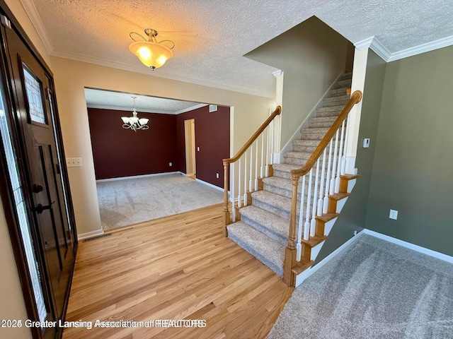 entryway featuring a textured ceiling, light wood-type flooring, crown molding, and baseboards