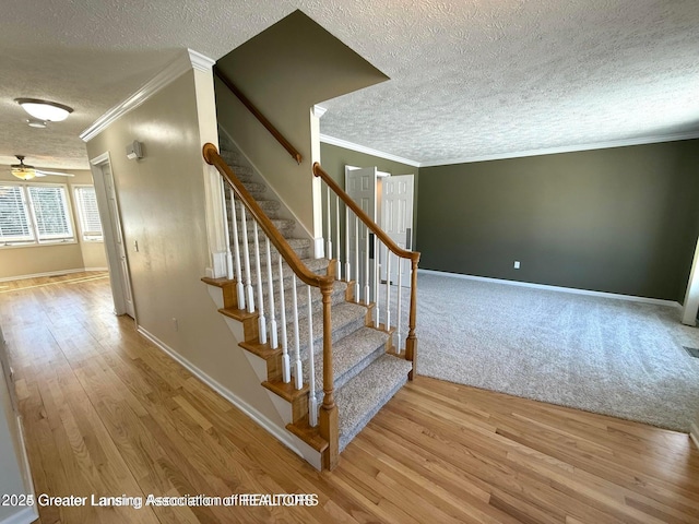 stairway with crown molding, wood finished floors, baseboards, and a textured ceiling