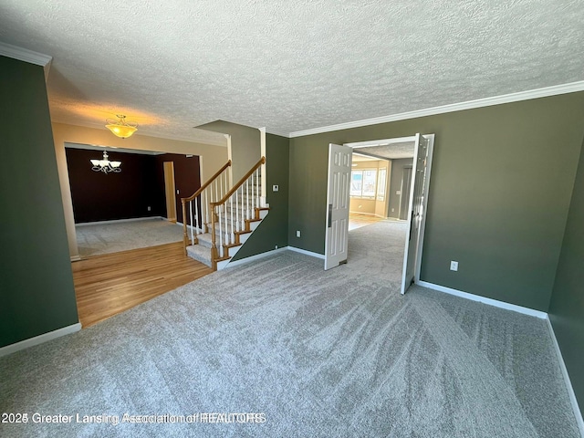 carpeted empty room with baseboards, an inviting chandelier, stairs, and crown molding