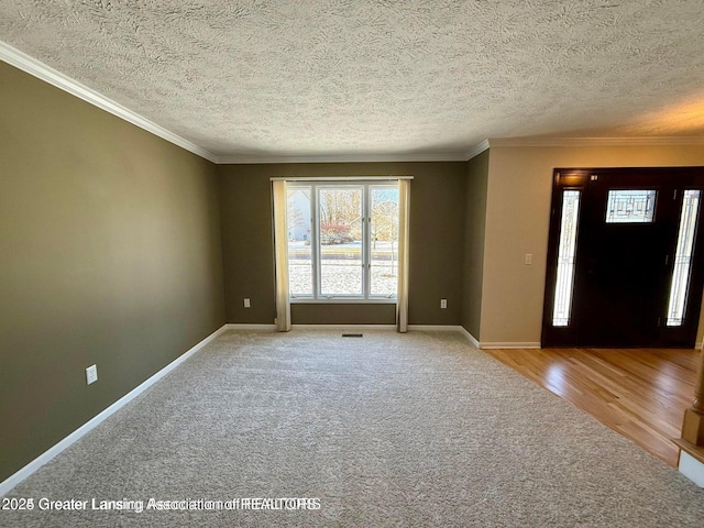 entryway featuring wood finished floors, baseboards, a textured ceiling, and ornamental molding